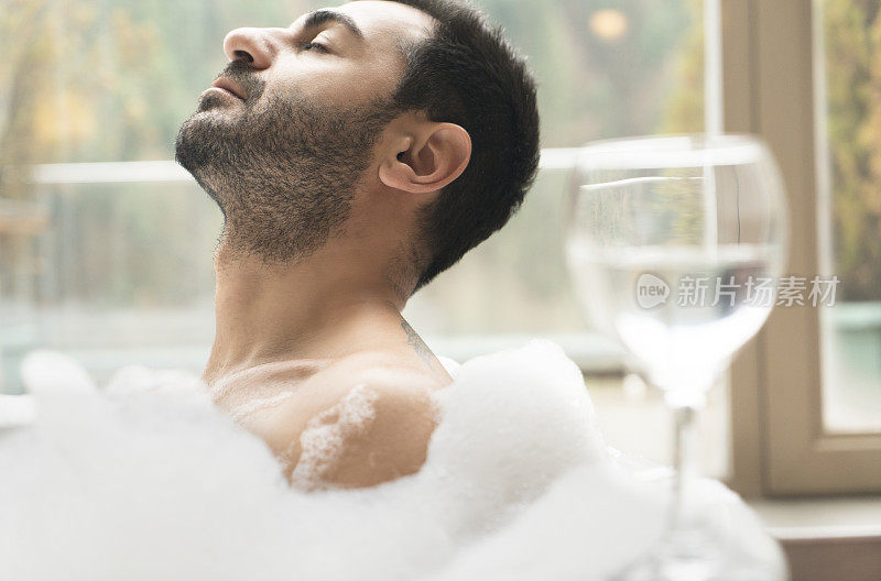 男人在热水浴缸与红酒杯在深度放松