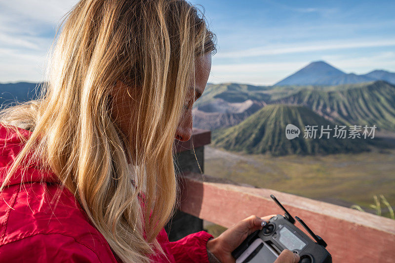 年轻女子使用无人机飞越火山景观——新科技人们旅游的概念