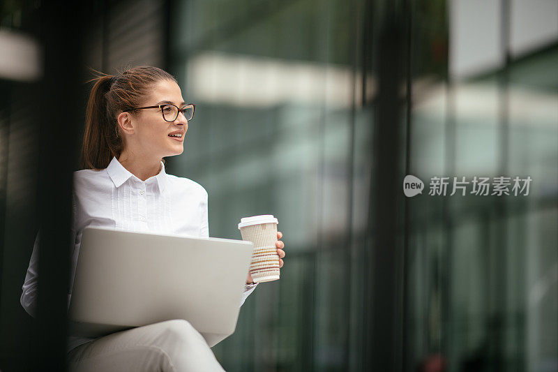 年轻漂亮的女商人一边打电话一边喝咖啡