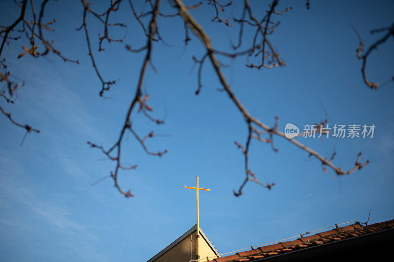 阳光下教堂上的金色十字架，德国