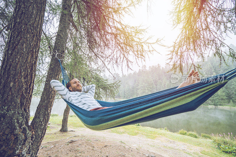 在瑞士山景中的吊床上放松的快乐的人