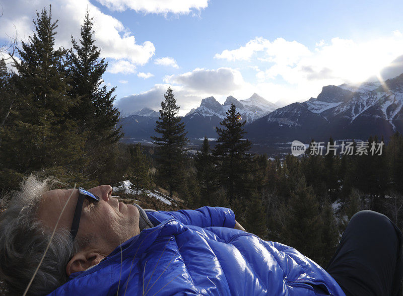 人斜倚在森林和高山之上的山坡上