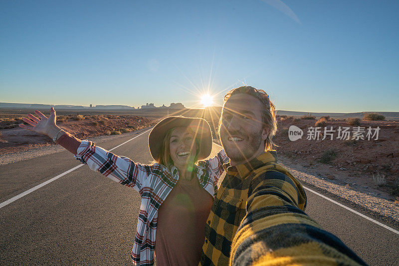 在美国旅行的夫妇在通向犹他州纪念碑谷的空高速公路上自拍;人的冒险旅行概念