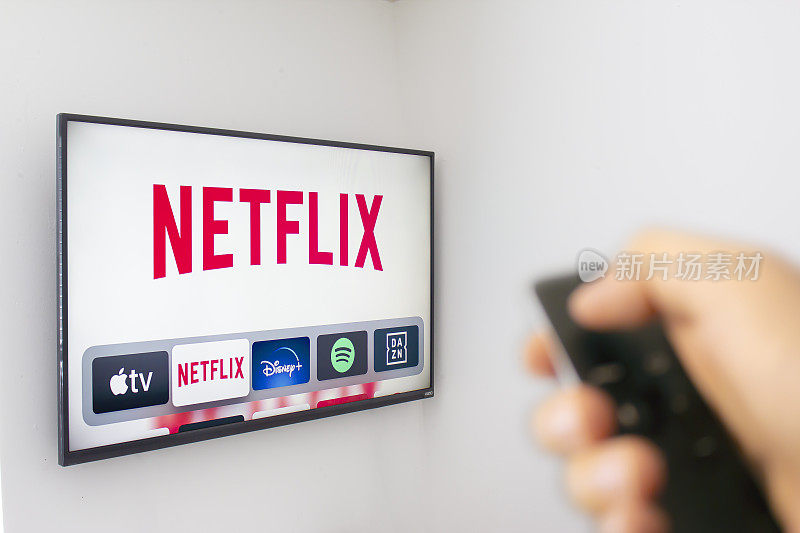 一个人用手拿着一个苹果电视遥控器，使用新的Netflix应用程序。Netflix主导了金球奖提名。说明