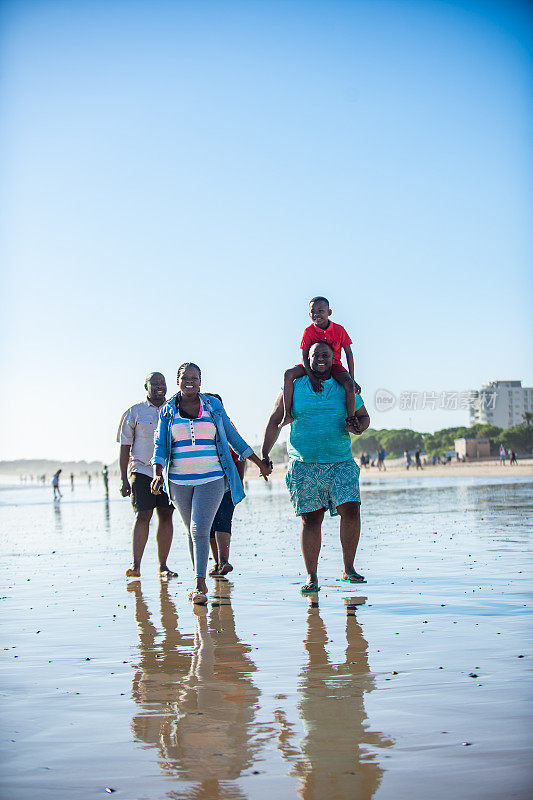 欢乐的多代家庭在海滩上散步