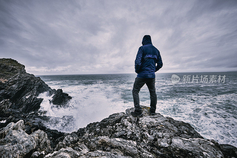 秋天的一个阴天，一个人孤零零地站在悬崖顶上望着大海。