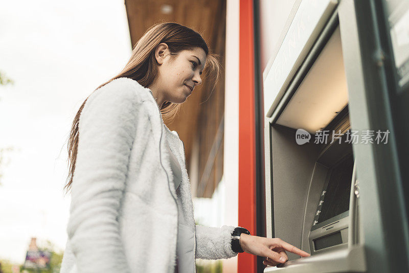 一个女人在自动取款机上查她的银行账户余额