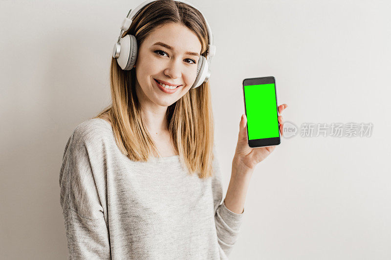 一位戴着耳机的年轻女子手里拿着手机，手机上有色度键显示