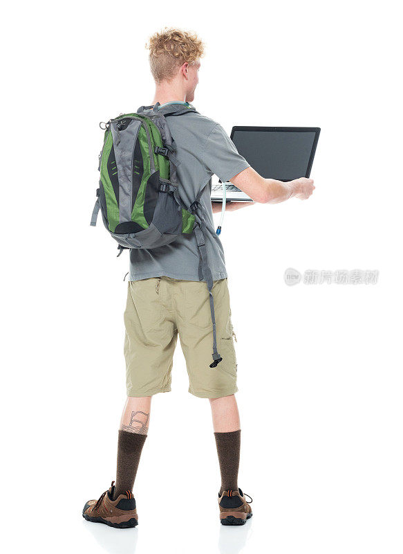 白人男性背包客在白色背景前背着背包，拿着包，使用电脑