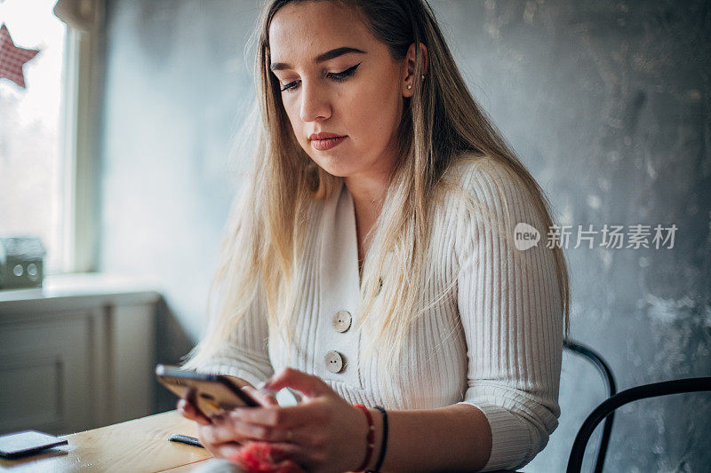 年轻女子在咖啡馆用手机发短信