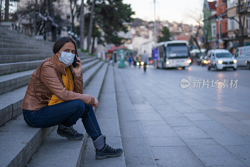 冠状病毒保护。妇女戴着口罩在城市里躲避传染病，下班后在等公交车。