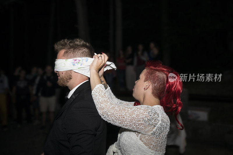 婚礼派对上的休闲游戏，新娘用眼罩套住新郎的眼睛