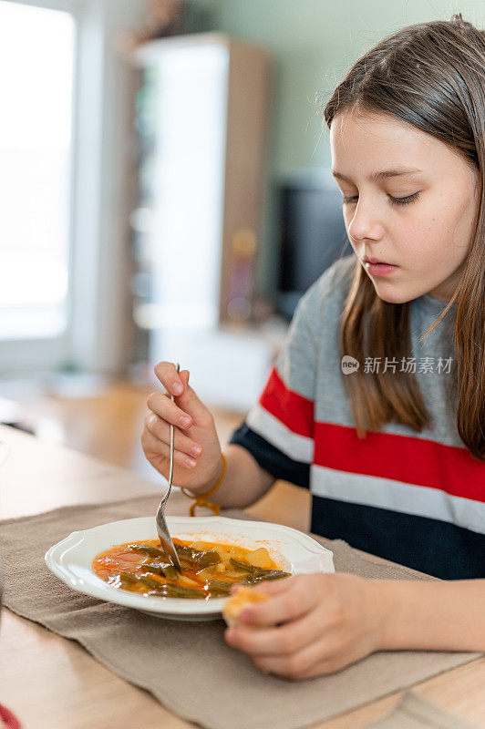 年轻女孩在家喝蔬菜汤