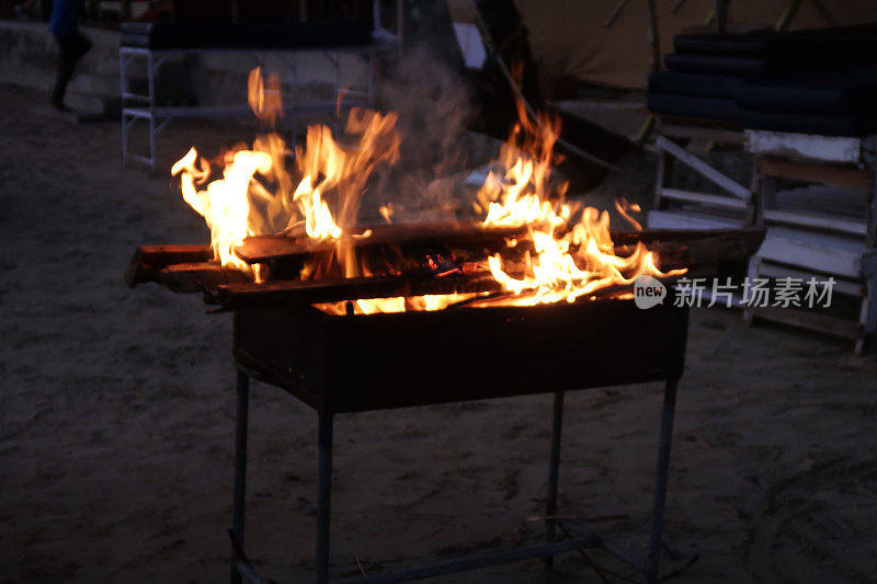 咆哮的，跳舞的火焰从海滩烧烤燃烧木材的夜晚天空，户外海滩餐厅