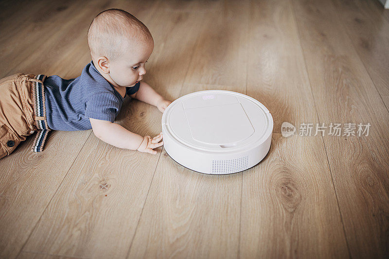 可爱的小男孩在家里玩，发现了机器人真空吸尘器