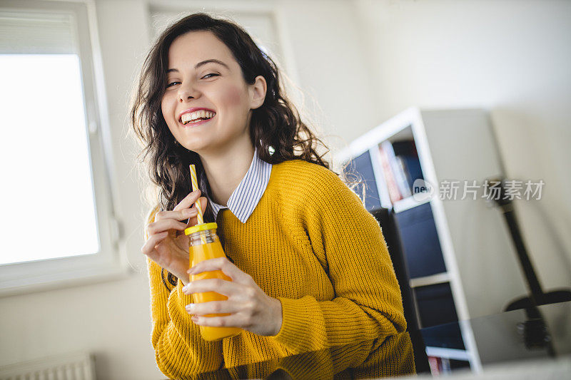 女学生在家里上网络课的时候喝着橙汁