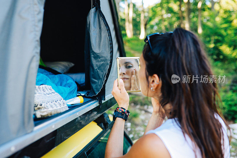 一名年轻女子在野营旅行的早晨涂抹护肤品