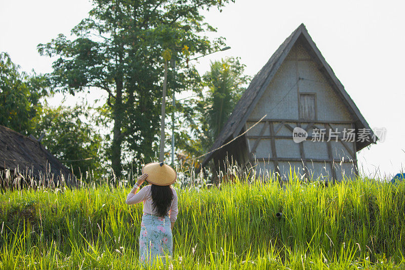 亚洲孕妇在稻田和她传统的房子里