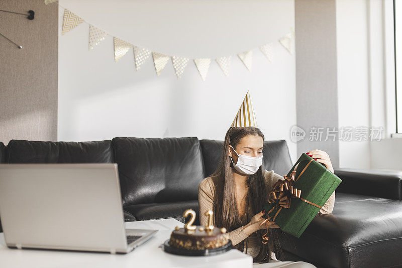 在新冠肺炎大流行期间，快乐的小女孩打开礼物，与朋友视频通话，庆祝自己的21岁生日