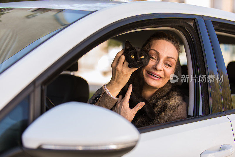 一个开朗成熟的女人抱着她的黑猫坐在车里