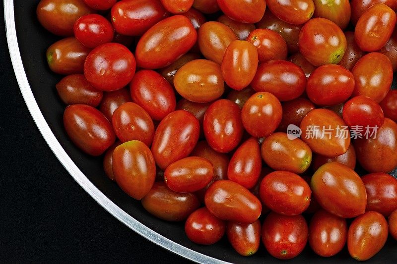 平底锅中的番茄-黑色背景。