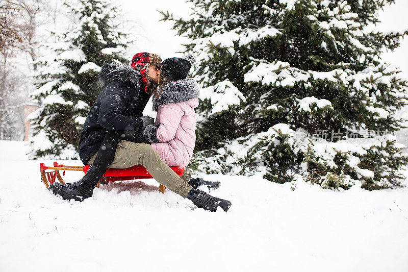 一对年轻的情侣在雪橇上接吻