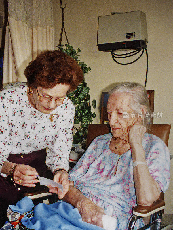 一位年长的妇女在给养老院的老妇人读信