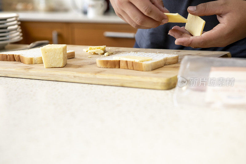 十几岁的孩子把奶酪片放在一块板上的白面包上