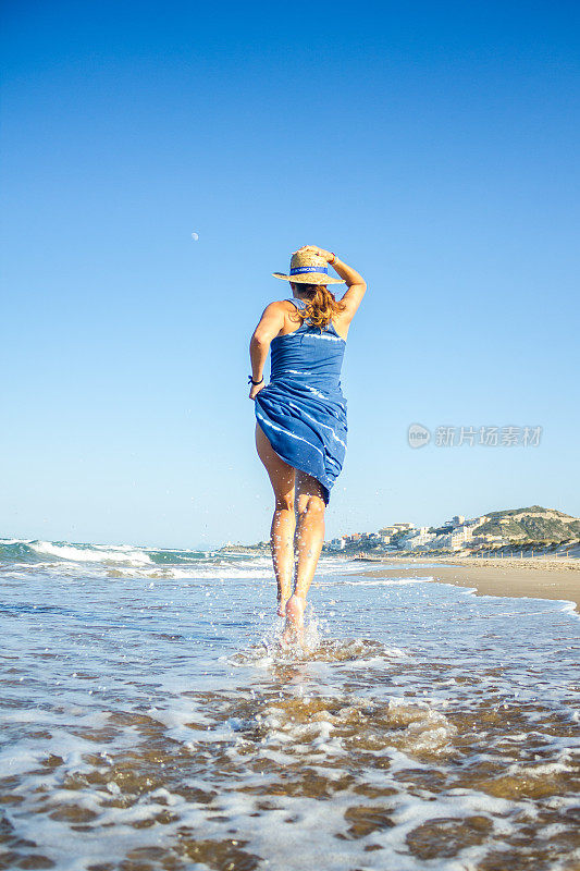 在夏天，活跃的女人独自沿着海滩的海岸奔跑。