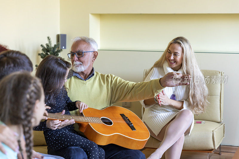 一位快乐的退休老人正在为他喜欢放松音乐的近亲弹吉他。