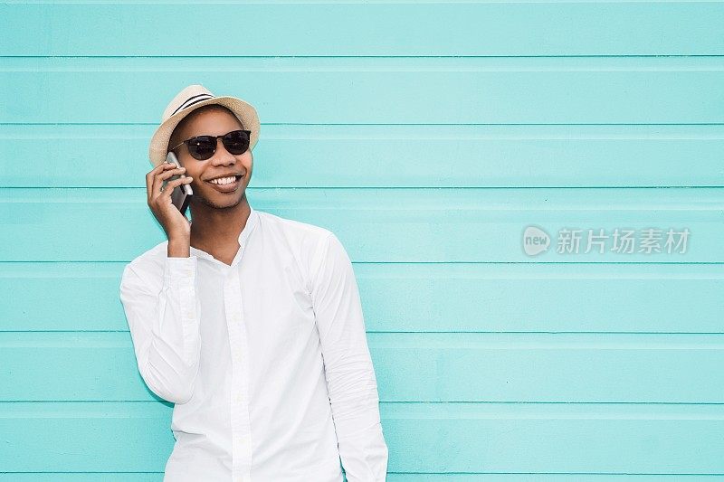 英俊的非洲或非洲裔美国人的肖像在街上使用他的手机。通信的概念。