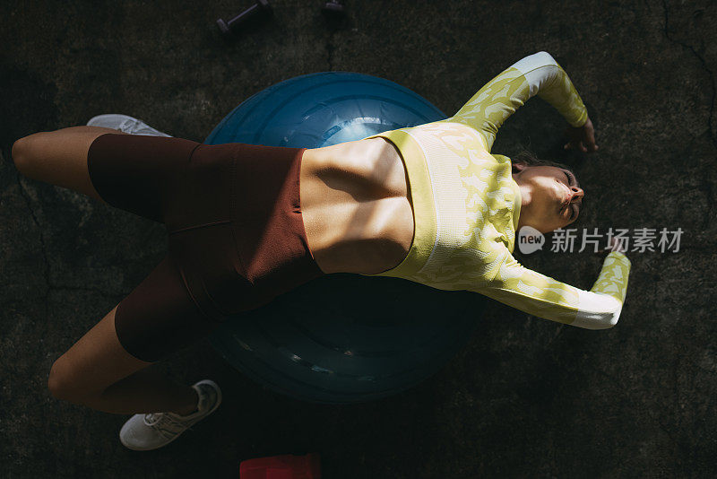 健身女人躺在普拉提球在健身房