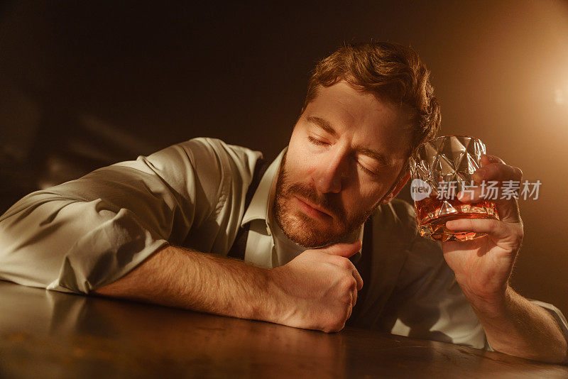 一个喝着威士忌的醉汉的大气肖像。这个人在思考或者已经睡着了，他的眼睛闭着。一个男人悲伤地拿着一个装满威士忌的美丽的多面玻璃，放在他的脸旁边。