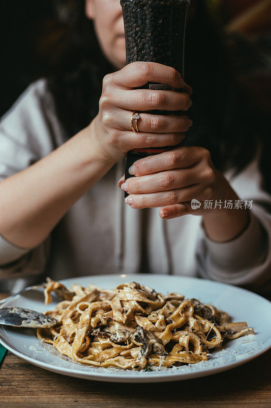 女人在意大利面里磨黑胡椒