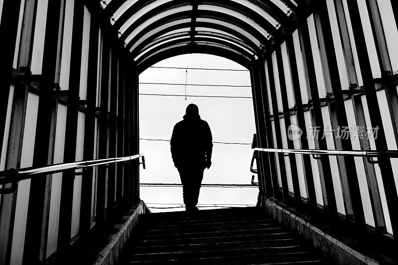 一个爬楼梯的男人的背影剪影，黑白