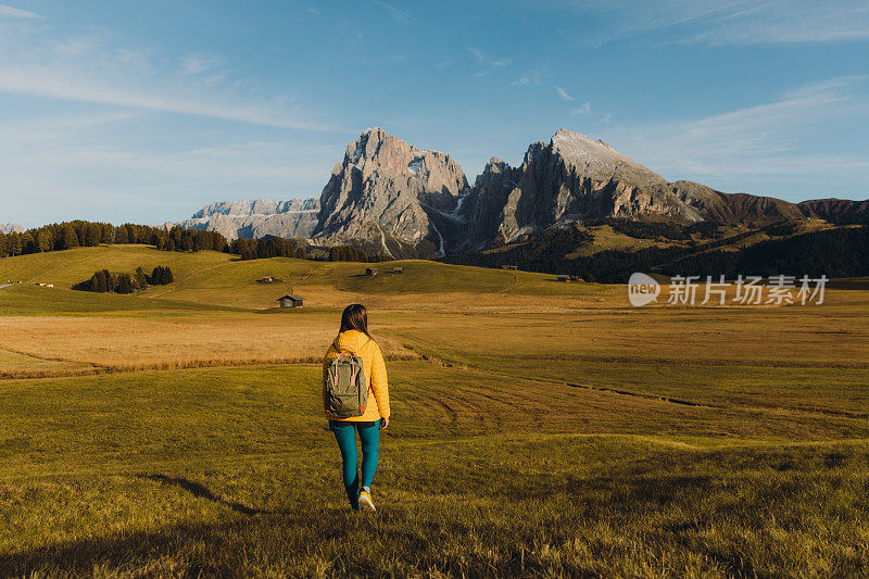 在白云石阿尔卑斯山脉的高山草地上散步，凝视夕阳美景的女游客