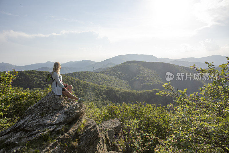 女徒步旅行者在日出时在观景台放松