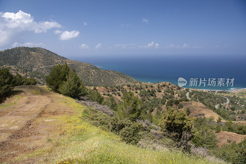 从防火路上的视线，沿着植被稀少的火山山坡蜿蜒到海边的村庄