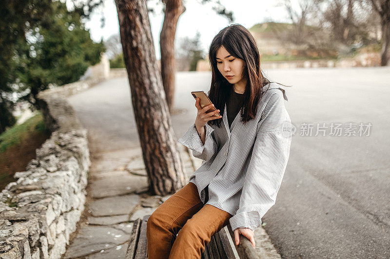 中国年轻女子在公园里玩智能手机