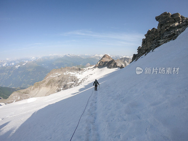 后视图的登山者在雪道上领先的方式，pov从伙伴后面连接到绳子