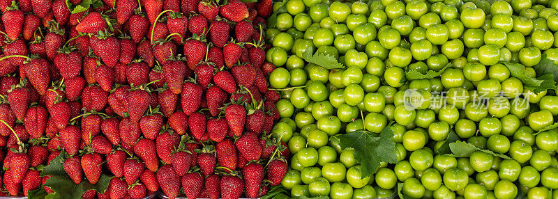 有新鲜有机水果和蔬菜的街市。与红草莓和青梅放在一起。对比和差异