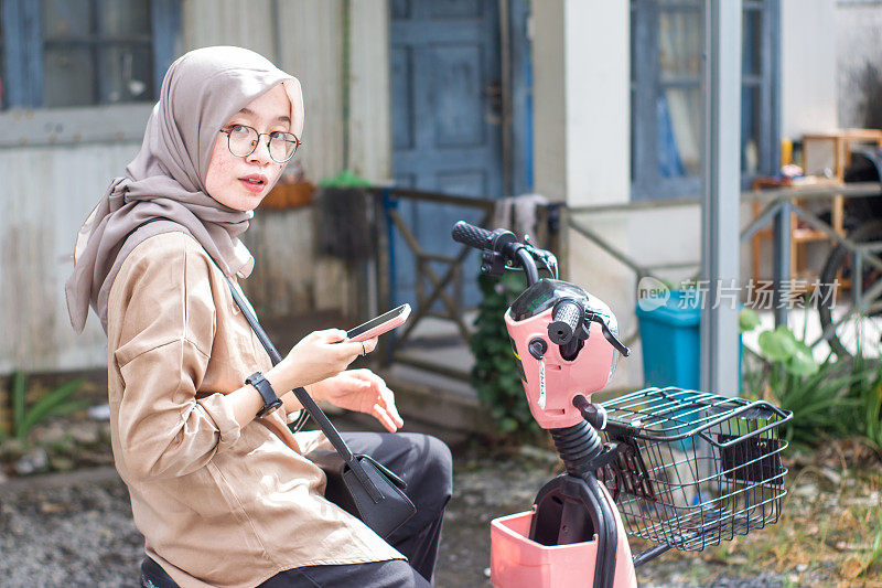 年轻的伊斯兰妇女在居民区骑电动自行车