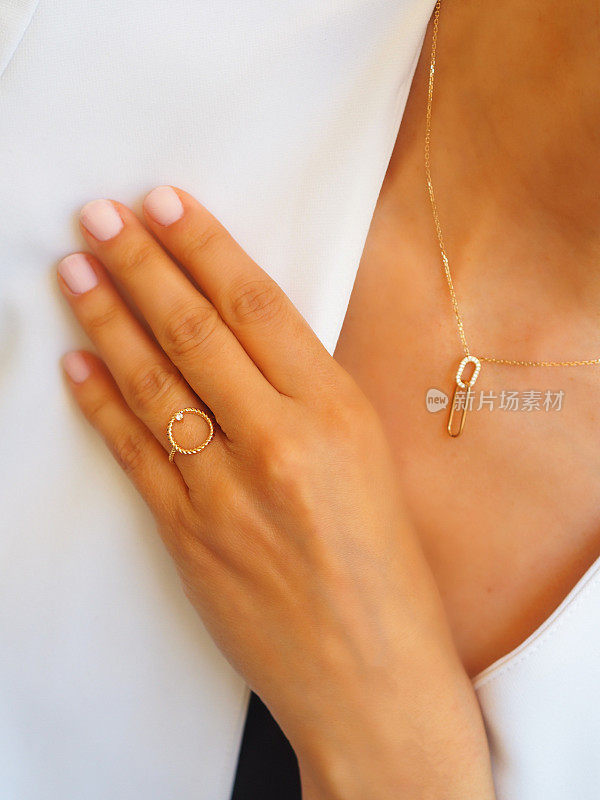 钻石金戒指和项链在一个女人的手上