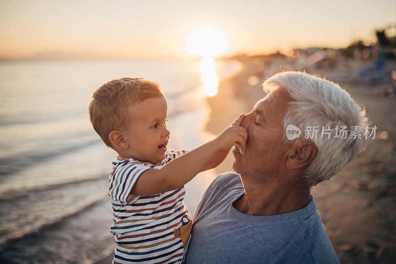 日落时分，爷爷和孙子在海滩上享受美好的一天