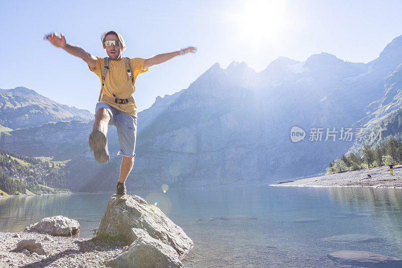 一个人在高山湖边从一块岩石跳到另一块岩石