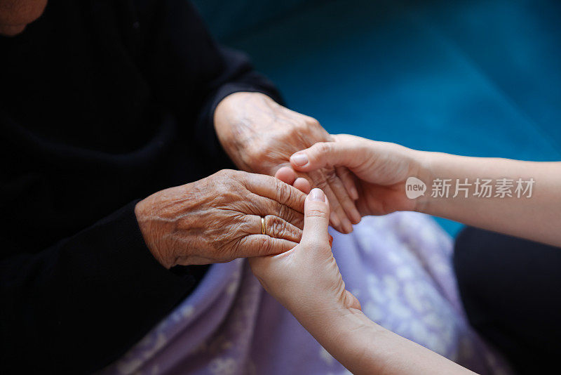 老女人的手牵着年轻女人的手，伸出援手，照顾老人的理念。