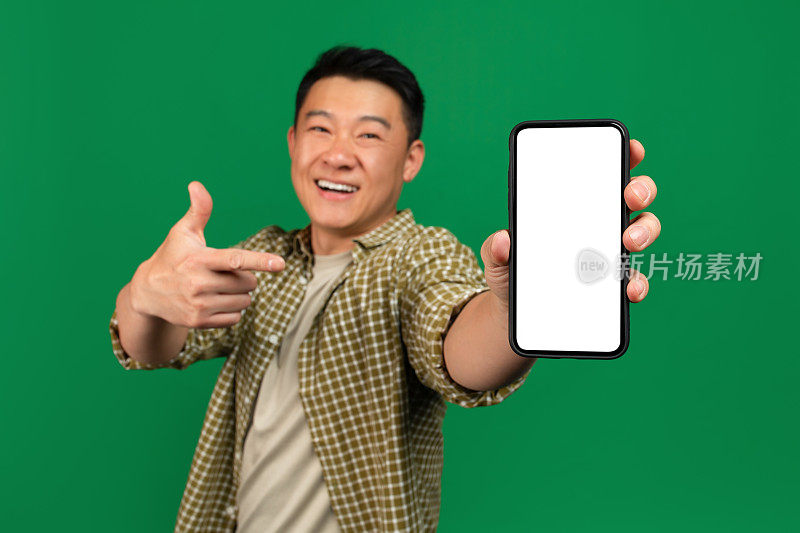手机应用广告。快乐的亚洲成熟男子指着空的智能手机屏幕，模型