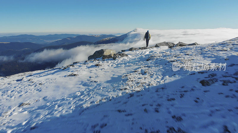 背包客在山谷上方的雪山上徒步旅行