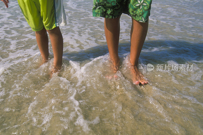 沙滩上穿着泳裤的男孩的腿