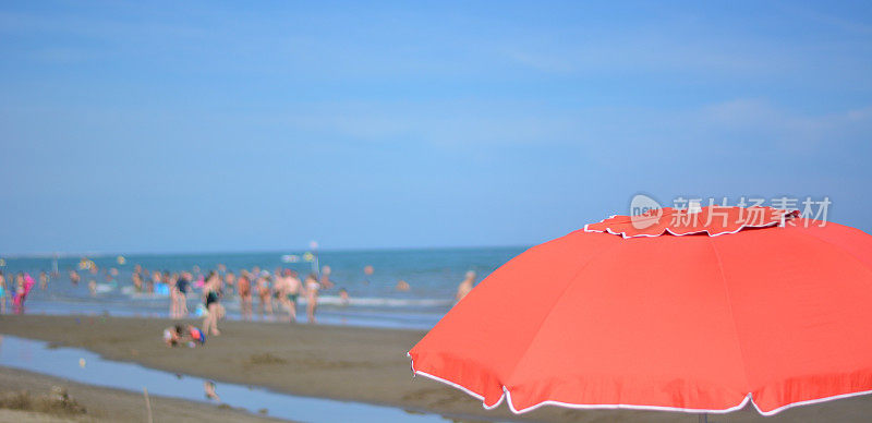 大海前一把敞开的红色沙滩伞